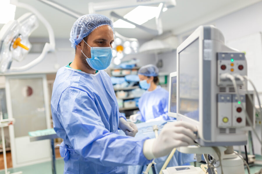 Anesthesiologist monitoring patient vitals and anesthesia equipment in an operating room during a surgical procedure.