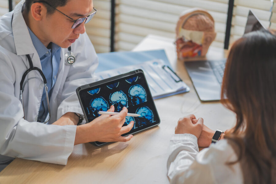 Neurologist reviewing brain MRI scans on a tablet with a patient during a neurology consultation