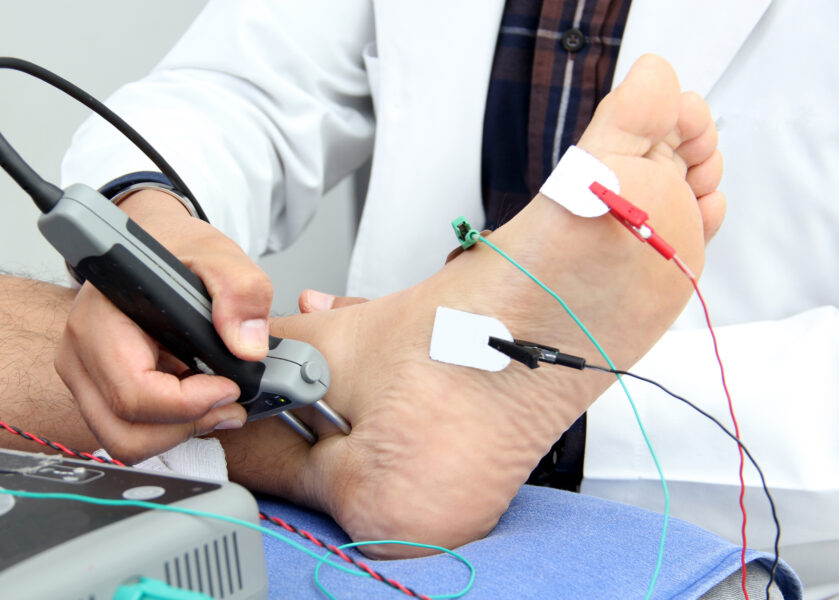 Neurologist performing a nerve conduction study on a patient's foot during an electrodiagnostic evaluation