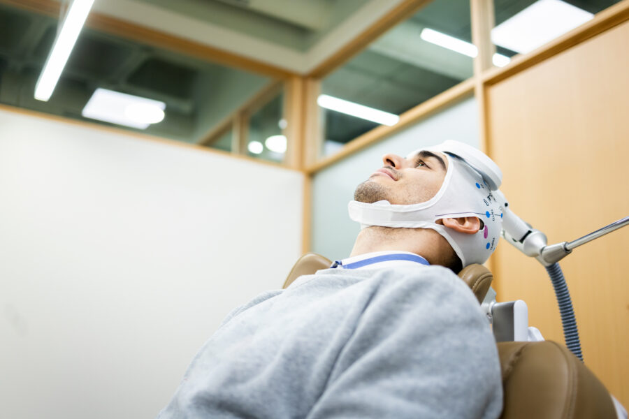 Patient undergoing transcranial magnetic stimulation therapy with a TMS device during a neurology treatment session