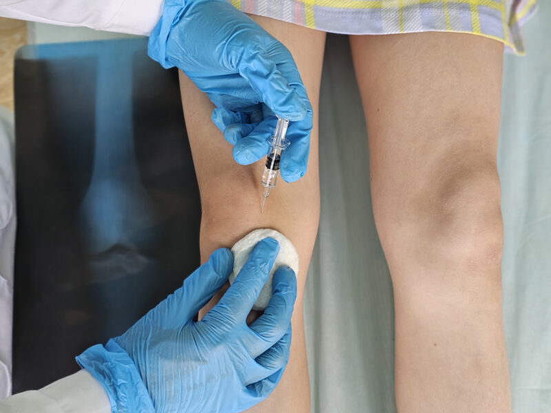 Physician administering a knee injection as part of interventional pain management care.