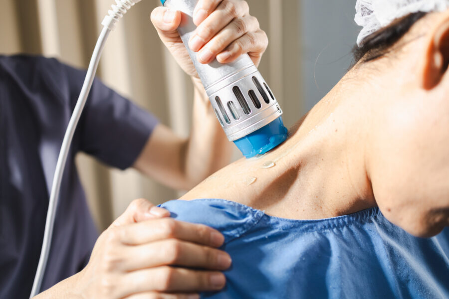 Pain management clinician applying a therapeutic device to a patient’s neck and shoulder area during a treatment procedure.