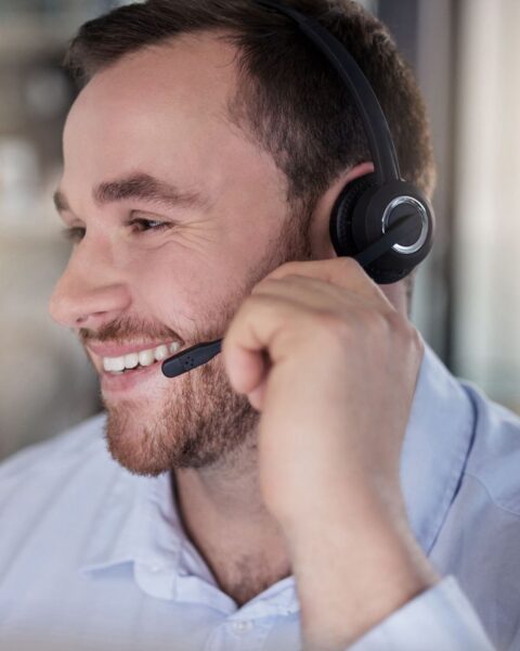 Customer support representative wearing a headset and speaking with a client, representing dedicated account management and billing support for pain management practices.
