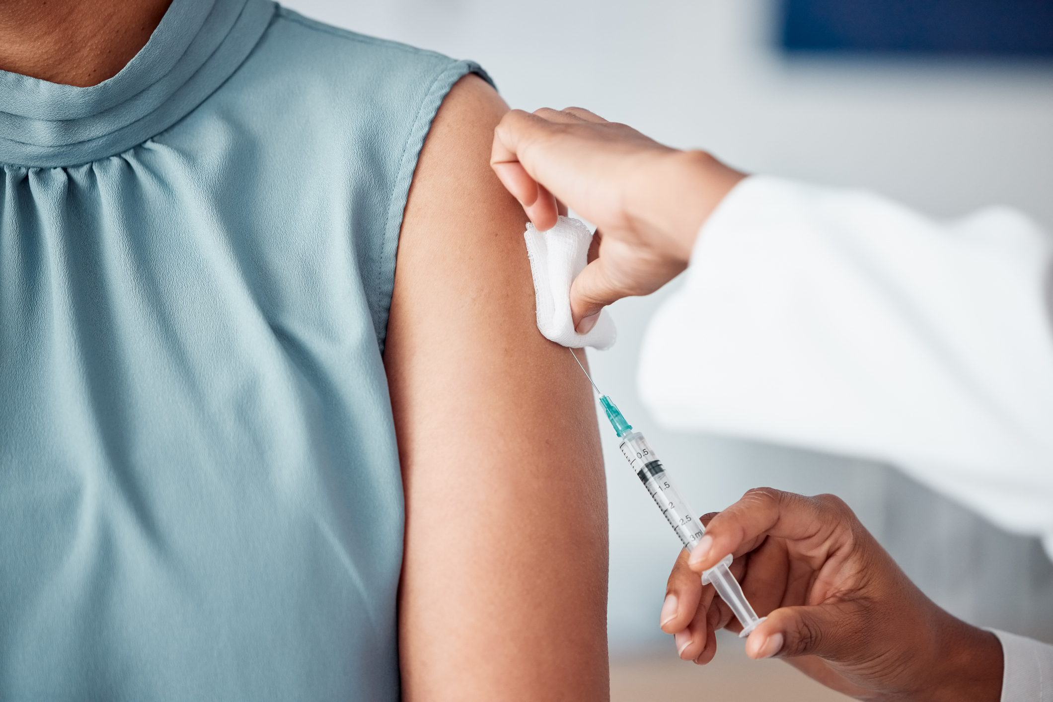 Close-up of a patient receiving a vaccination in the upper arm during a primary care visit.