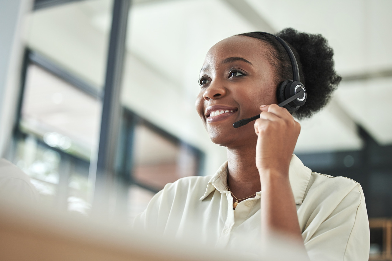 Primary care billing specialist communicating with a medical practice over the phone while wearing a headset in an office setting.