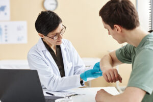 Portrait of mature female doctor inspecting patient with skin rash during consultation in dermatology clinic